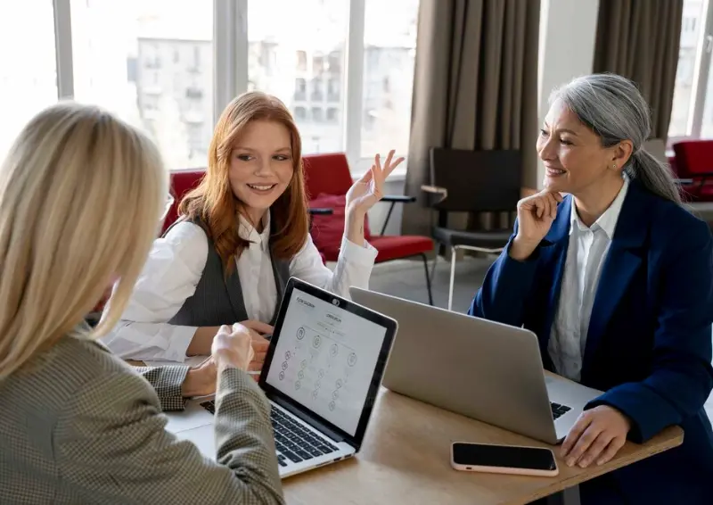 Three women collaborating over laptops in a business directory office meeting